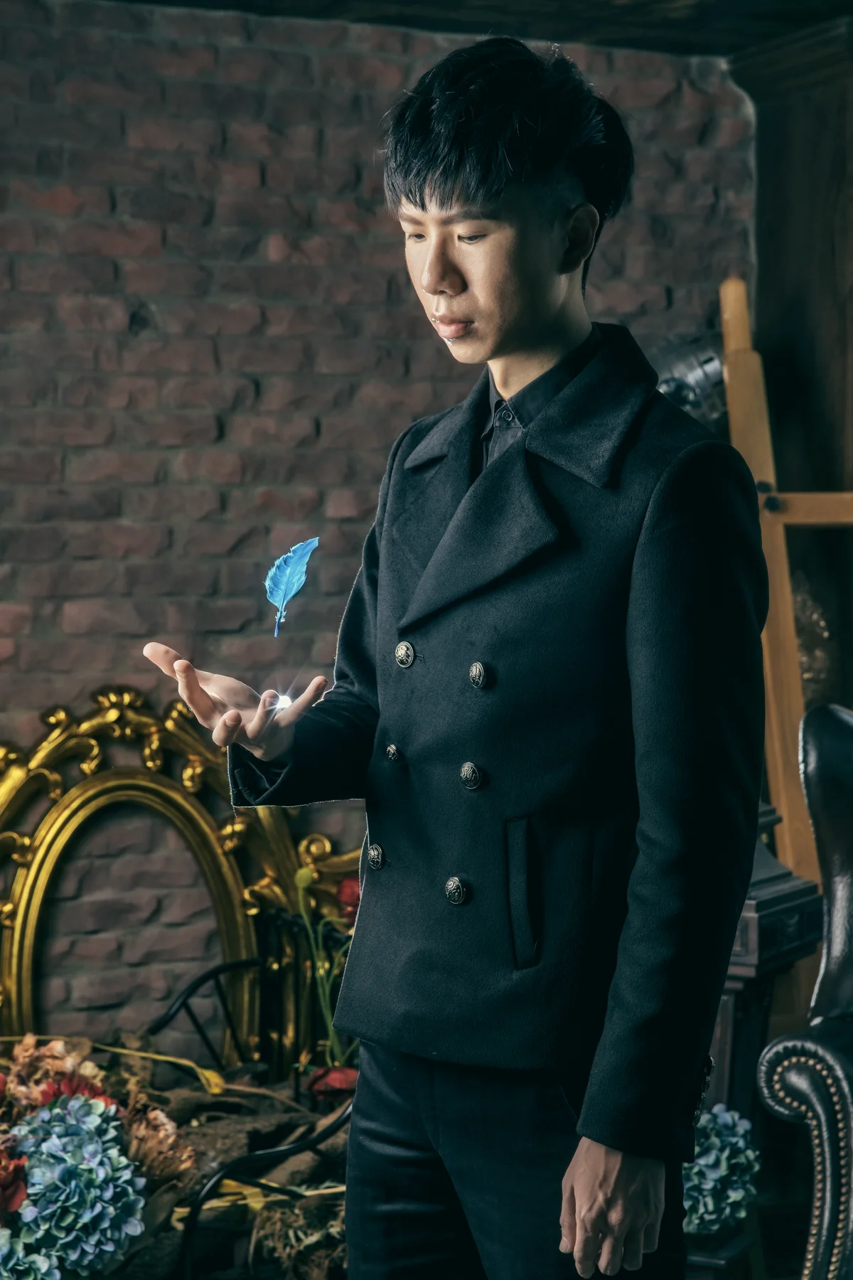 魔術師彭品文身穿黑色外套，手掌上方浮著藍色羽毛
