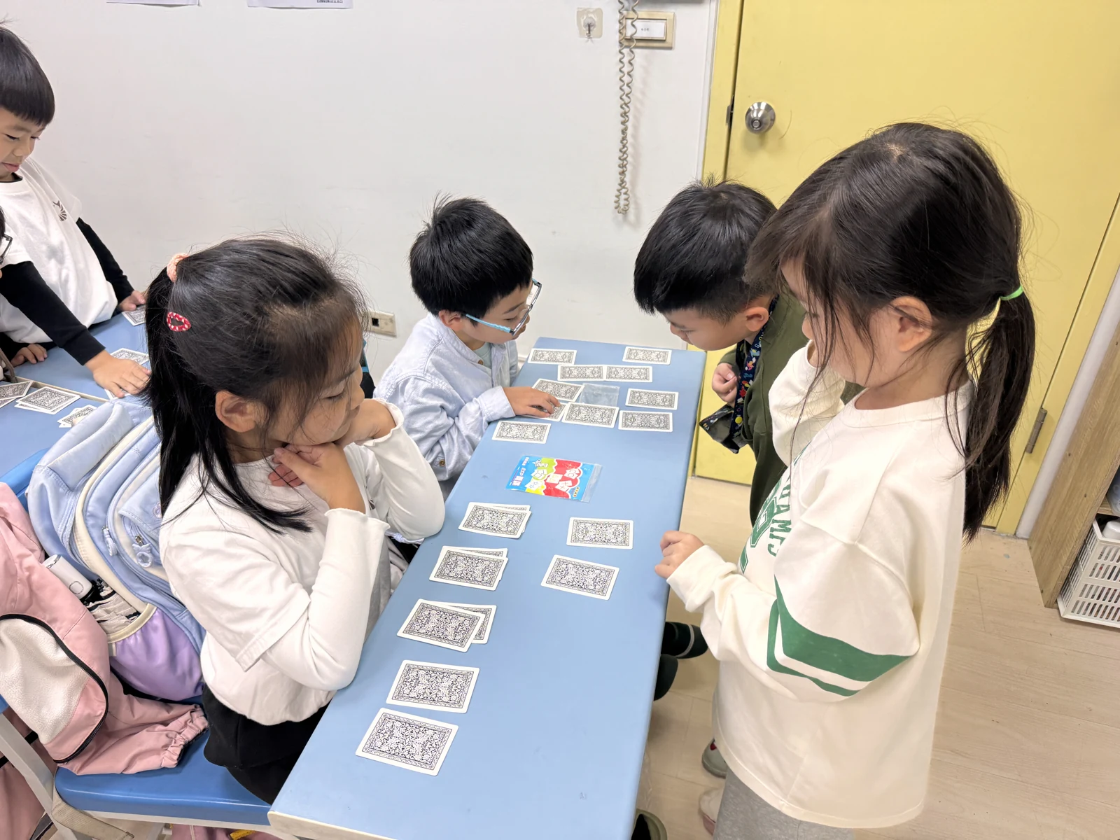 三位學員圍桌操作撲克牌，互相練習魔術步驟