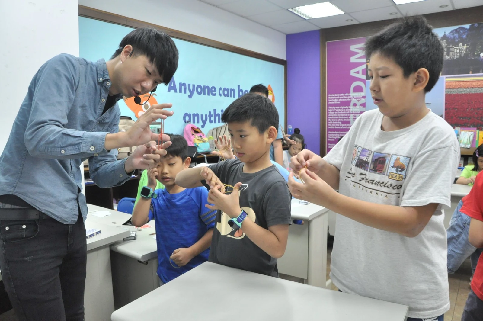 講師在學員身旁示範手部動作，孩子跟著操作