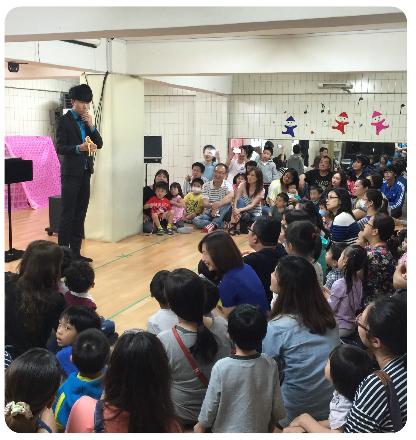 魔術師在孩子與家長面前演出,觀眾圍坐欣賞