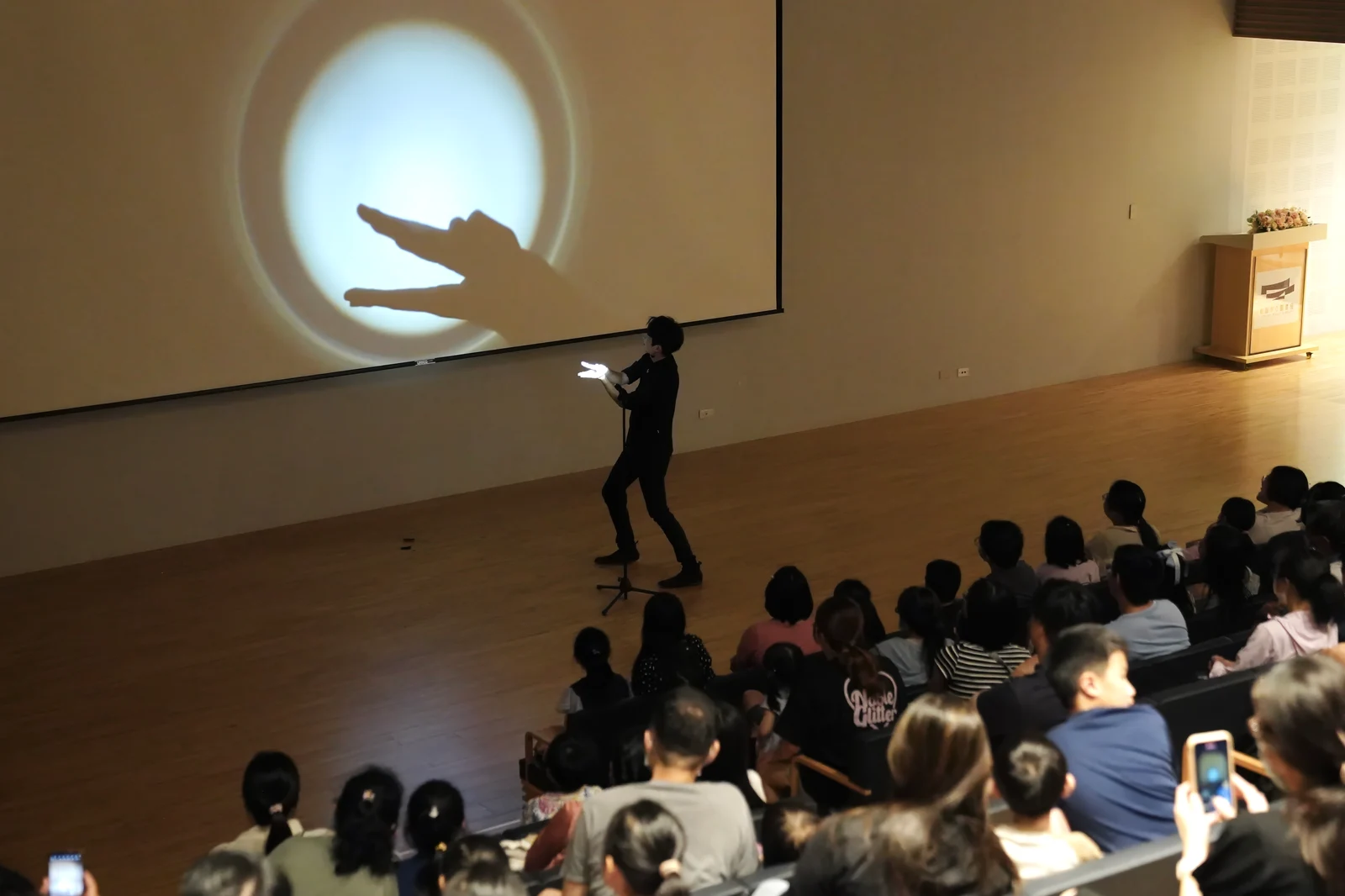 手影表演者在觀眾前以雙手呈現大型動物影像